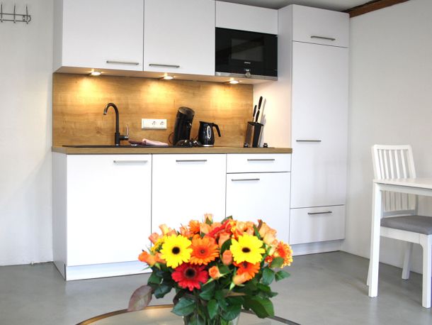 Moderne Küchenzeile mit Holzoptik, Kaffeemaschine und Besteckblock im stilvollen Business-Apartment bei Stuttgart