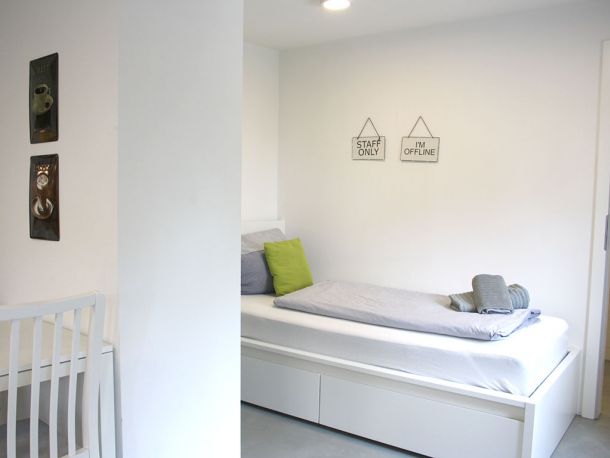 Schlafbereich mit Einzelbett, Wanddeko und frischer Bettwäsche im modernen Business-Apartment bei Stuttgart