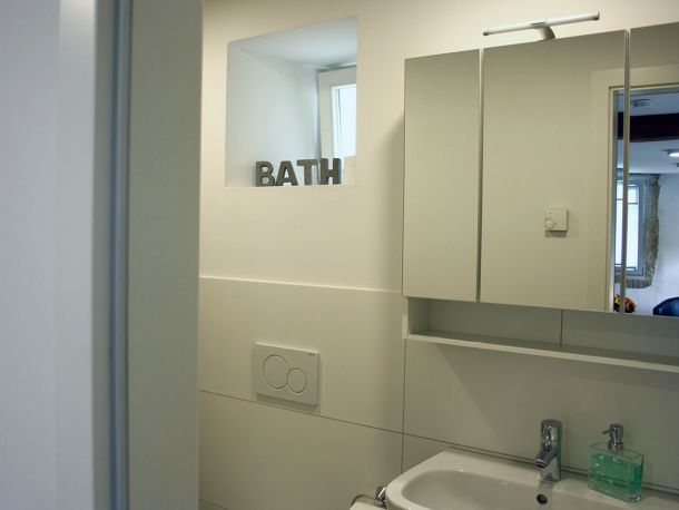 Modernes Tageslichtbad mit Spiegel, Waschbecken und schlichter Dekoration im Business-Apartment bei Stuttgart